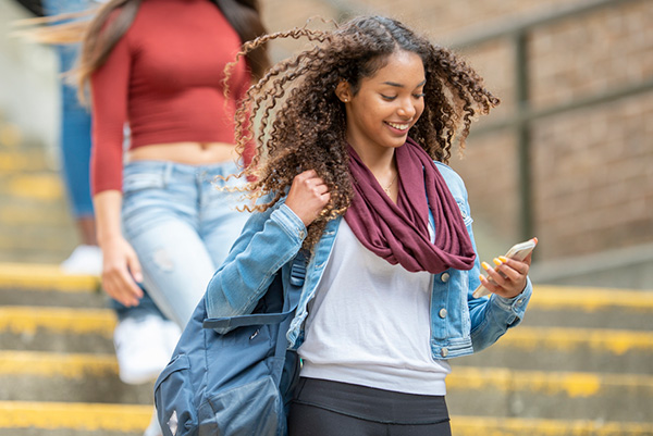 University student walking while holding her phone